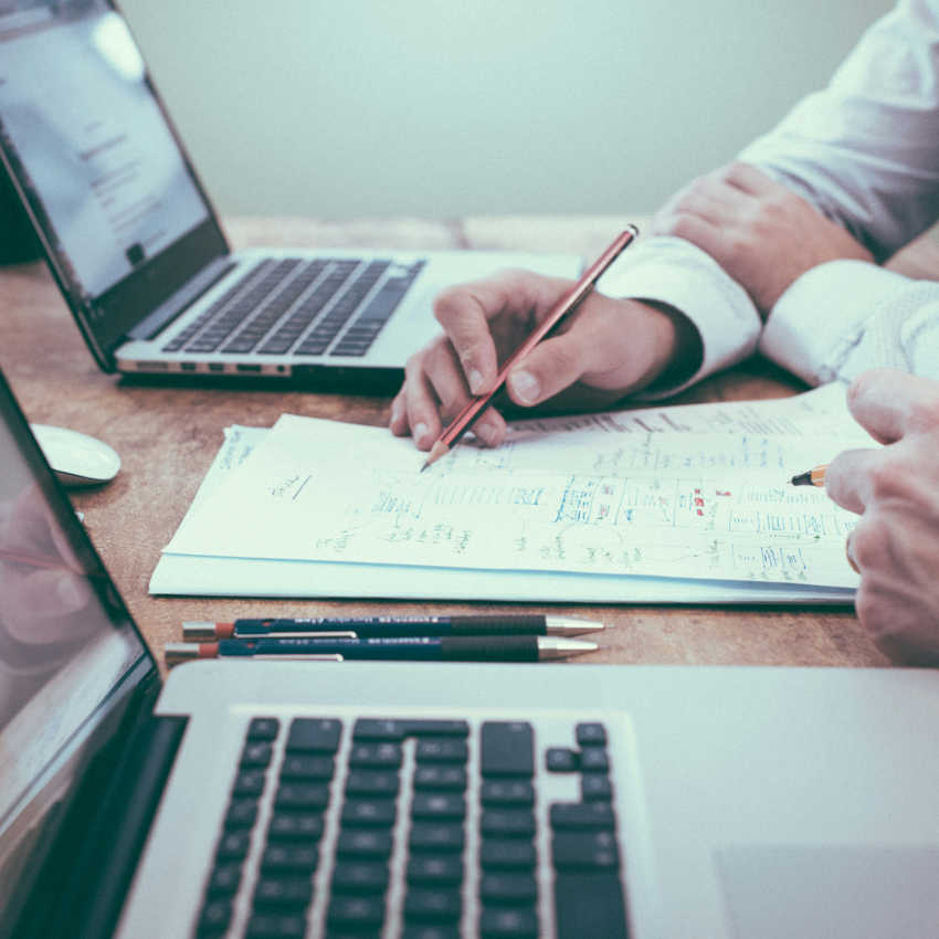 Hands reviewing printed results next to laptops