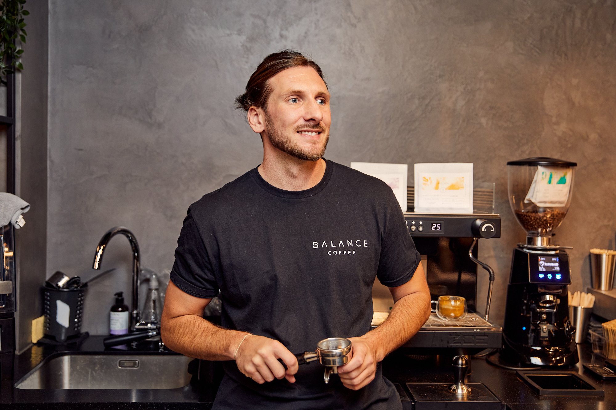 James, founder of Balance Coffee, holding a portafilter beside the espresso machine