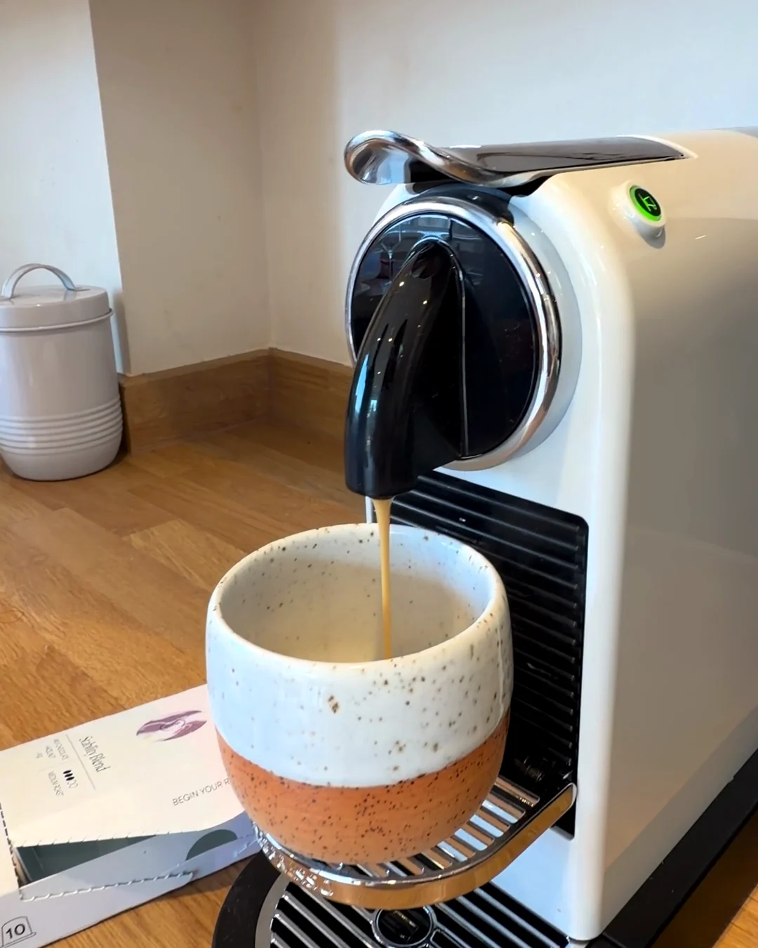 An espresso shot pouring into a warmed cup