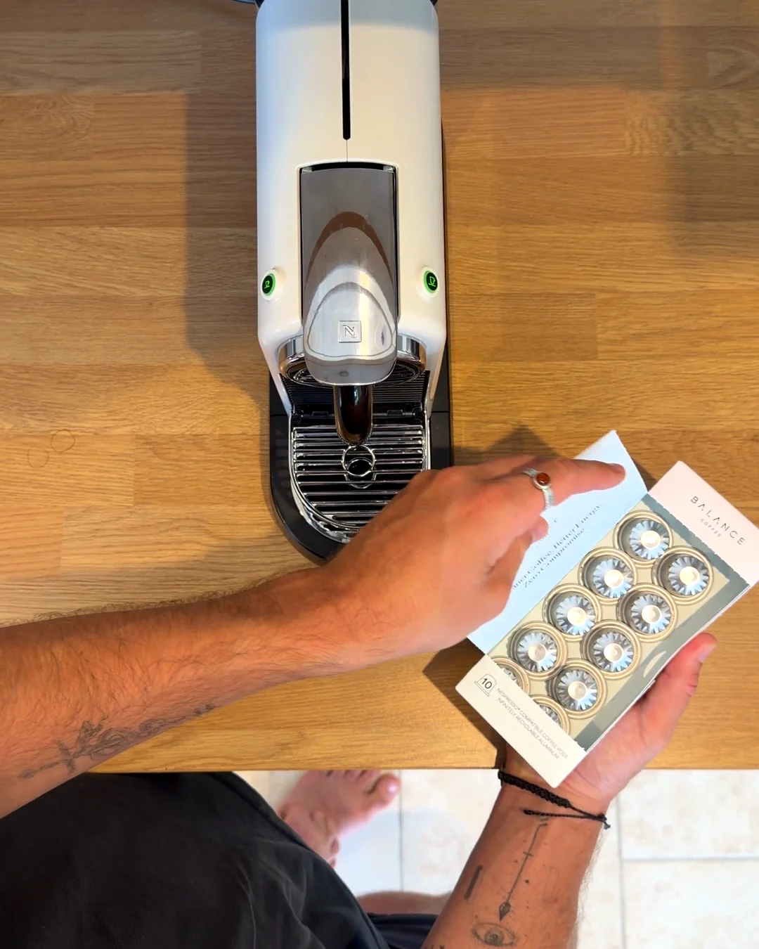 A hand taking a Clean Coffee Pod from the box next to the machine